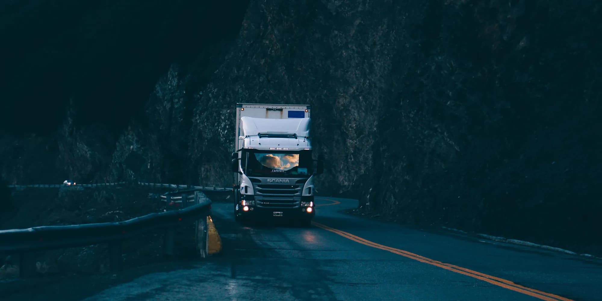 Articulated truck running an open trunk road at dusk